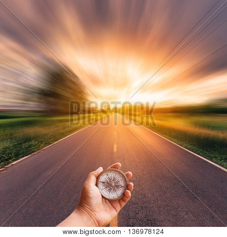Hand Man Holding Compass On Blurred Road With Sky Sunset.