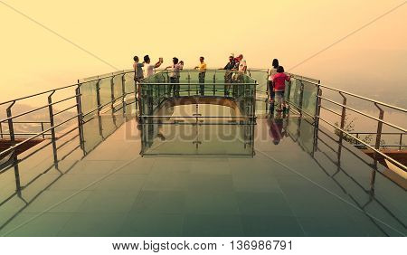 Nong Khai province Thailand- April 28 2016: Tourists walking and taking photograph on transparent sky walk to see view of Mekong River during sunset at Wat Pha Tak Suea Sangkhom district Nong Khai province Thailand.