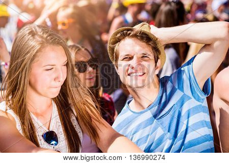Teenagers at summer music festival under the stage in a crowd enjoying themselves