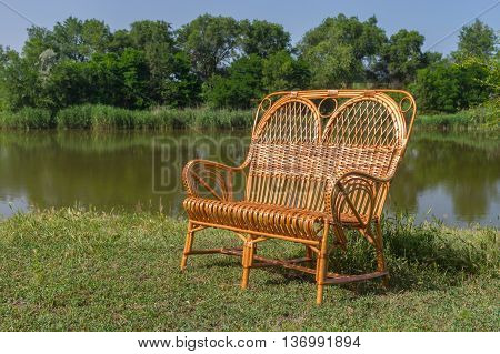 Wicker wide chair on a lakeside at summer season