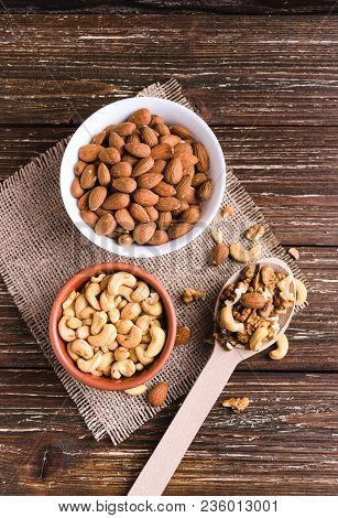Differrent Variety Of Nuts - Walnuts, Cashew, Almond In Bowls And Wooden Spoon. Rustic Scratched Woo
