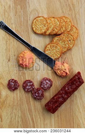 Wood Cutting Board With Dry Salami Stick, Crispy Crackers And 
Port-wine Spreadable Cheese For After