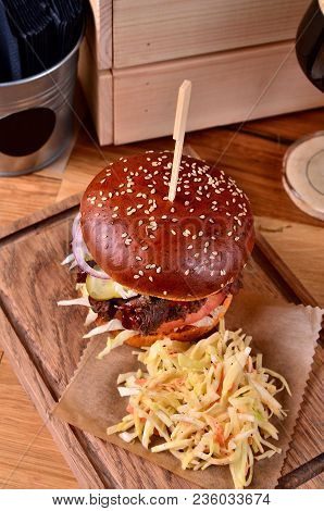 Top View Fresh Homemade Hamburger With Beef, Onion, Sause And Cabbage Garnish And Dark Beer On A Woo