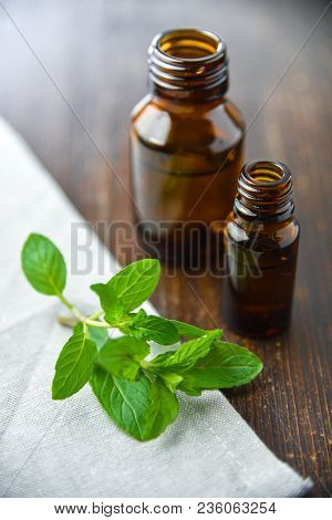 Essential Oil Of Peppermint In A Small Brown Bottle With Fresh Green Mint On An Old Wooden Backgroun