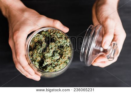 Top View. A Can With Buds Of Cannabis In The Hands Of A Man. The Concept Of Legal Marijuana Is Medic