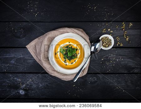 Pumpkin Soup With Jusai And Fried Cilantro, Served In White Bowl With A Spoon And Linen Napkin, On T