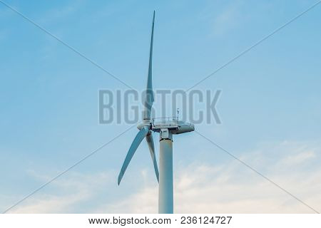 White Windmill Against Cloudy Sky With Copyspace.