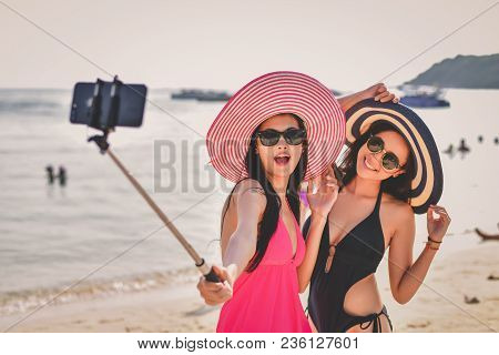 Swimsuit Concept. Beautiful Girl Wearing A Swimsuit Playing Mobile On The Beach. Beautiful Girl Is T