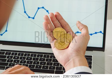 Man Holding Bitcoin And Background With Smart Phones, Laptops And Business Graphs - Concepts For Sta