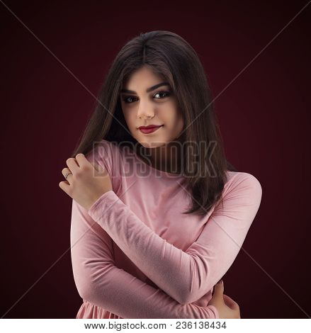 Brunette Woman In Pinc Dress With Long And Shiny Wavy Hair . Beautiful Model On Red Background. Stud