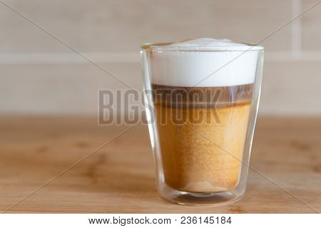 Multilayer Coffee Or Cappuccino In A Glass Cup On Wooden Table.