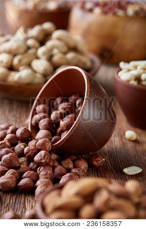 A Composition From Different Varieties Of Nuts In A Wooden Bowls Over Rustic Background: Hazelnuts, 