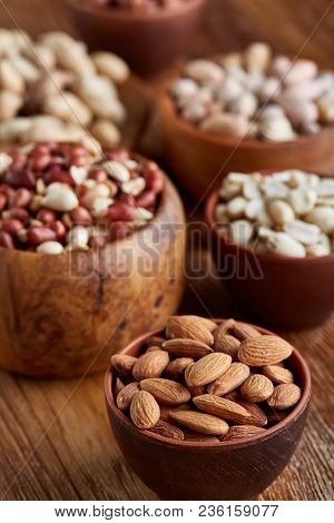 A Composition From Different Varieties Of Nuts In A Wooden Bowls Over Rustic Background: Hazelnuts, 