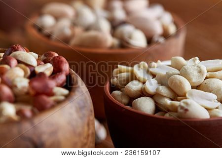 A Composition From Different Varieties Of Nuts In A Wooden Bowls Over Rustic Background: Hazelnuts, 