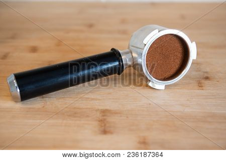 Portafilter With Temping Ground Coffee On Wooden Table.