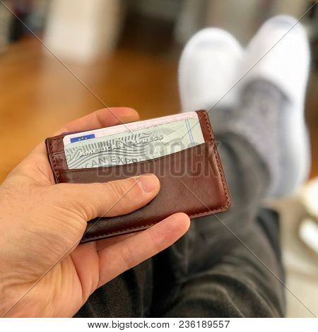 LONDON - APRIL 15, 2018: A man holds a leather wallet containing an American Express credit card in London, UK.
