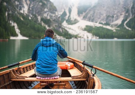 The Guy Is Sitting In A Boat And Starts To Row, Against Lake La-go Di Brize