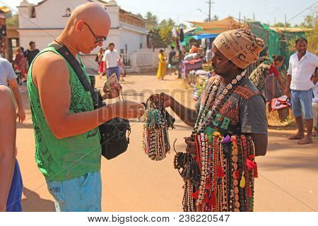 India, Goa, January 24, 2018. Street Trading. Bald Tourist European Buys Beads Or Jewelry From An In