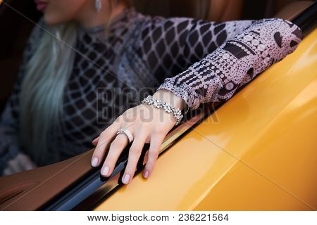 Beautiful Woman With Yellow Sport Car. Young Female Model With Lixury Diamonds Jewerly Sitting In A 