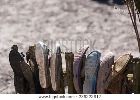 Picture Of Poverty In Old Worn House Slippers On Wooden Fence. Space For Text