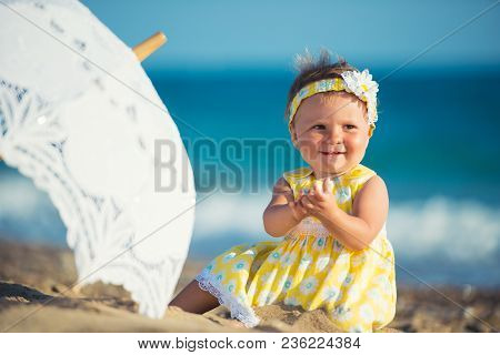 Lovely Little Girl On The Beach With An Umbrella.