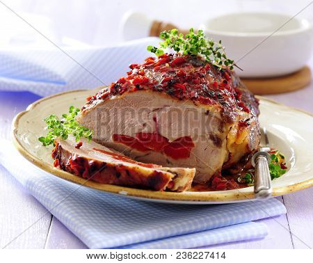 Roast  Glazed Pork Loin Stuffed With Sweet Red Pepper Garnish With Herbs And Chili.