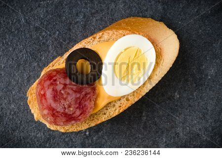 Open faced sandwich canape or crostini on dark stone background closeup. Top view.