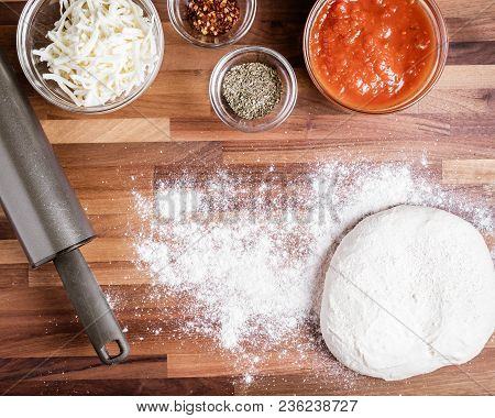 The Ingredients For Making Homemade Pizza, Including Shredded Cheese, Pizza Sauce And Spices