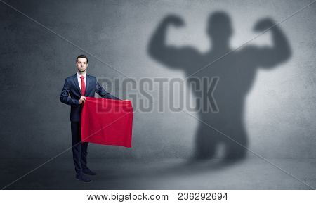 Businessman standing with red cloth on his hand and strong hero shadow on the background
