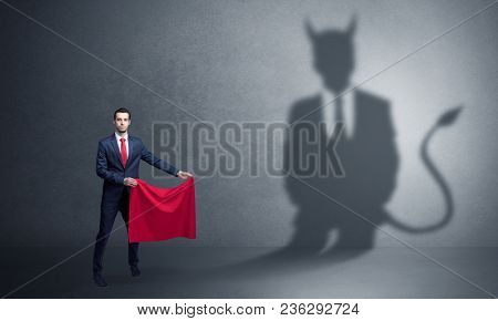 Businessman standing with red cloth in his hand and devil shadow on the background