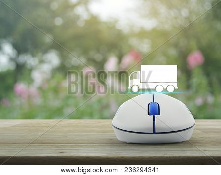 Truck Flat Icon With Wireless Computer Mouse On Wooden Table Over Blur Pink Flower And Tree, Busines