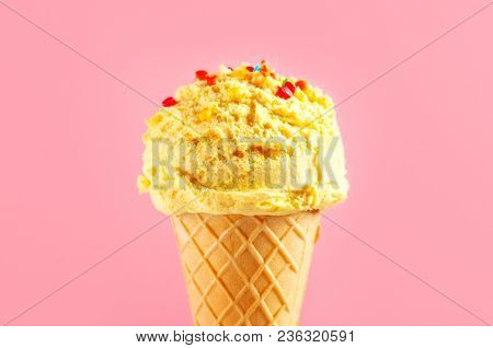 Ice cream cone close-up. Yellow Icecream scoop in waffle cone over pink background. Lemon flavor Sweet dessert decorated with colorful sprinkles, closeup