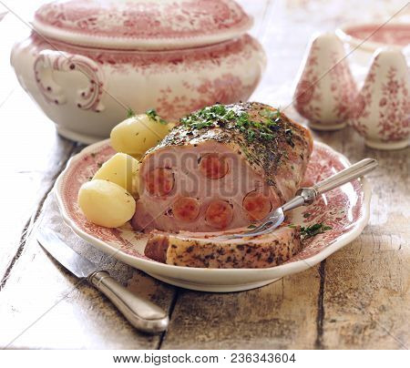 Roast Pork Loin Stuffed With Sausages Served With Baked Potato.