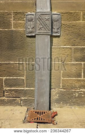 A Handcrafted Square Lead Downpipe With An Ornate Lead Bracket Fixed To A Stone Wall.