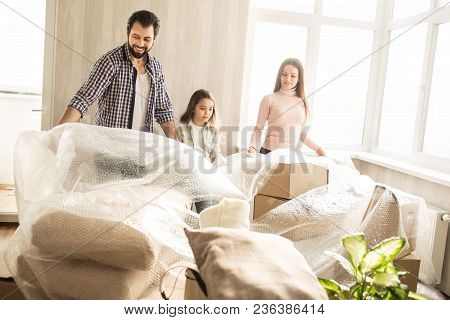 Beautiful And Friendly Family Are Unpacking Their Stuff. They Are Putting Off The Cover Of Boxes. Th