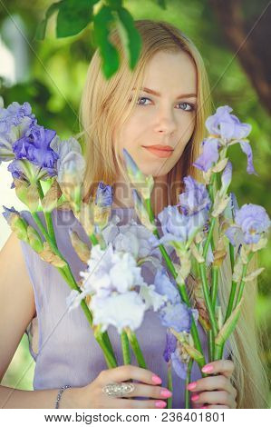 Attractive Young Girl With Blonde Dren Hair And Natural Make-up Smelling Blue Purple Iris Flowers On