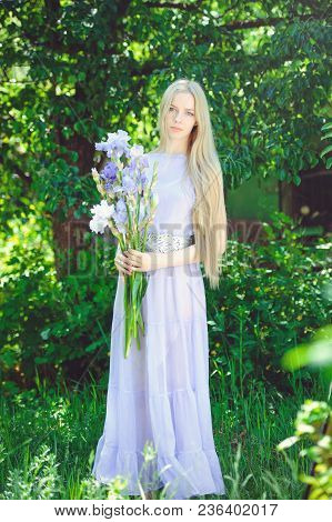 Attractive Young Girl With Blonde Dren Hair And Natural Make-up Smelling Blue Purple Iris Flowers On