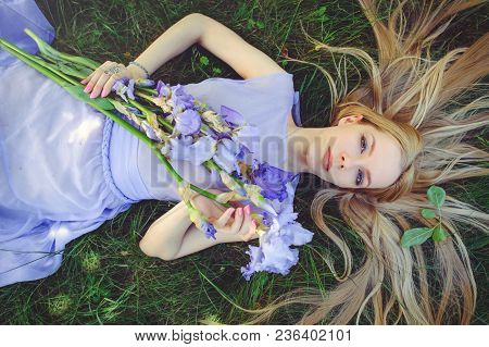 Attractive Young Girl With Blonde Dren Hair And Natural Make-up Smelling Blue Purple Iris Flowers Ly