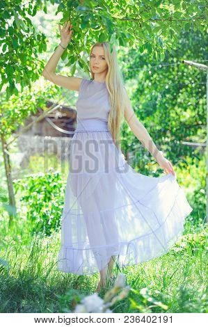 Attractive Modest Young Girl With Blond Dren Hair And Natural Make-up In Purple Dress Outdoors, Tend