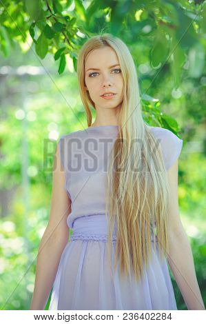 Attractive Modest Young Girl With Blond Dren Hair And Natural Make-up In Purple Dress Outdoors, Tend