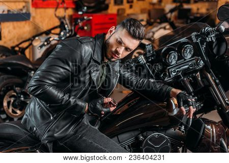 Stylish Rockabilly Man Sitting On Bike At Garage