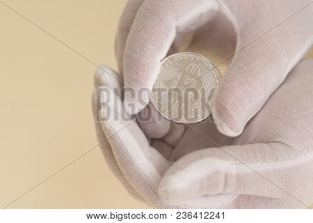 Hands In White Gloves Carefully Hold A Coin Bitcoin. Hope For Capital Growth