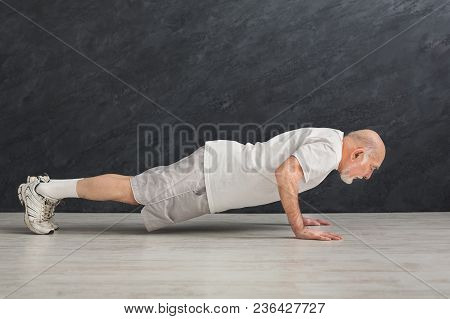 Senior Man Workout In Fitness Club. Side View On Mature Caucasian Guy Making Plank Or Push Ups Exerc
