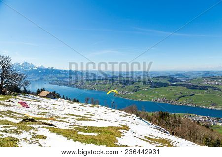 Beautiful Nature View In Swiss Alps With Paraplane Flying Over The Lake