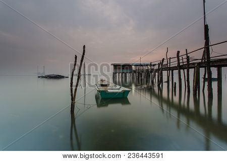 Cloudy Long Exposure Sunrise Shot At Jetty. Image Contain Certain Grain Or Noise And Soft Focus When