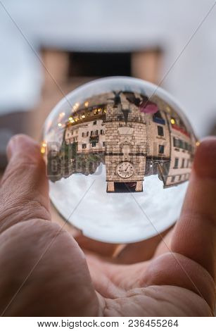Man Holding Transparent Glass Ball Reflecting The Old Clock Tower - A Kotor Landmark, Montenegro