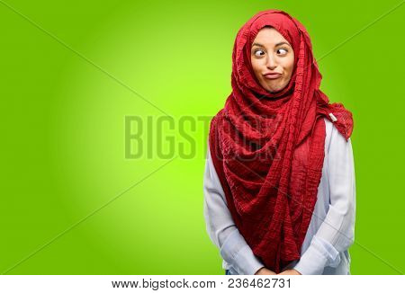 Young arab woman wearing hijab making funny face fooling