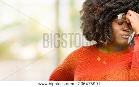 Beautiful african woman with sleepy expression, being overworked and tired, rubbes nose because of weariness, outdoor