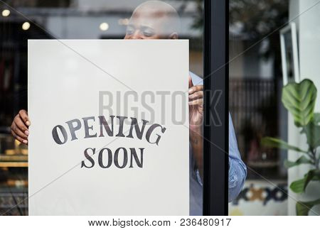 Man putting on store opening soon sign