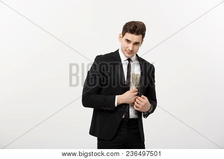 Business Concept: Handsome Businessman In Black Suit Taking Dollars Banknotes With Stealthy Expressi